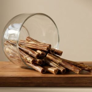 Cinnamon sticks spilling from a glass jar onto a wooden cutting board or countertop.