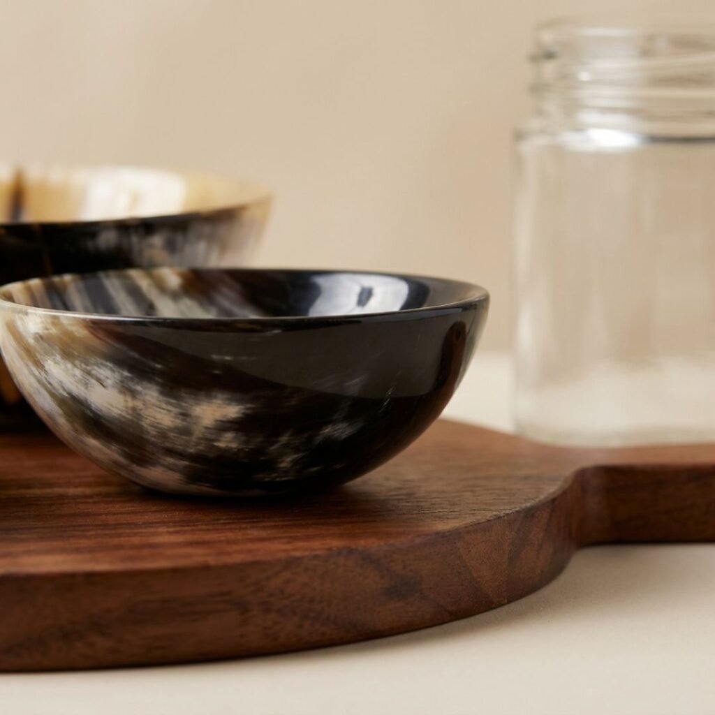 Black-and-white marbled ceramic bowls stacked on a wooden board, with a glass jar in the blurred background.
