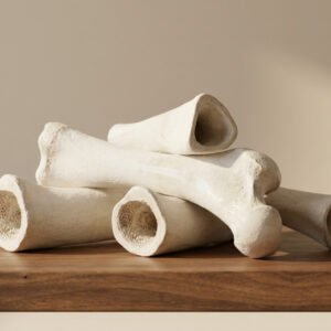 Pile of white bone-shaped objects stacked on a wooden surface.