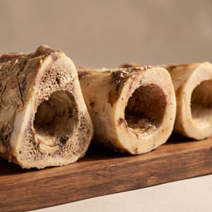 Cross-section of a bone-in roast on a wooden board, showing hollow marrow cavities and browned crust.