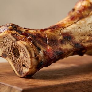 Cross-section of a roasted beef rib bone on a wooden cutting board, showing tender meat and exposed marrow.