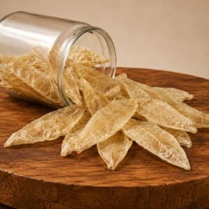 Dried flat, beige chip-like sheets spilling from a glass jar onto a wooden table.